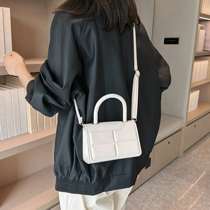 Minimalist white textured crossbody handbag with sleek handle and adjustable strap