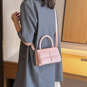 Pink quilted rectangular handbag with detachable strap shown on grey blazer