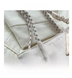 Detail of cream tote bag featuring textured geometric pattern and polka dot silk scarf