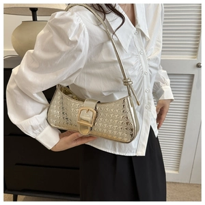 Détail d'un sac demi-lune doré avec gaufrage pied-de-poule étoilé et boucle métallique