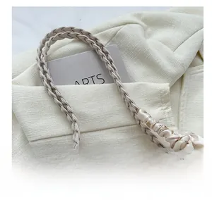 Detail of woven handles with floral silk scarf on beige textured tote bag