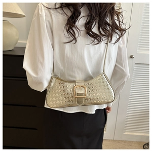 Sac baguette chic en cuir verni pied-de-poule avec boucle dorée porté à l'épaule