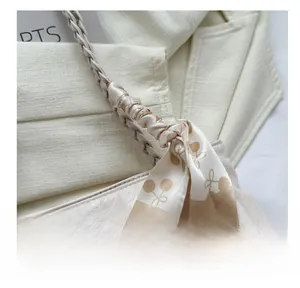 Detail of cream tote bag with star geometric embossing and printed silk scarf handle