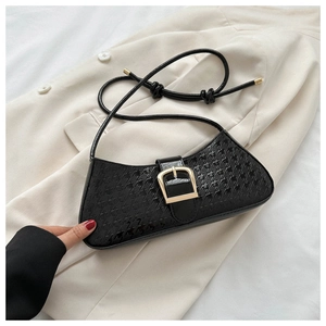 Détail du sac baguette en cuir verni noir avec gaufrage étoiles sur blazer blanc