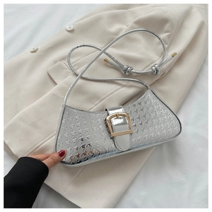 Détail d'un sac argenté métallisé avec gaufrage en étoile et boucle dorée sur un blazer