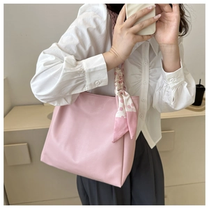 Pink tote bag detail with decorative silk scarf and woven shoulder strap in a mirror selfie