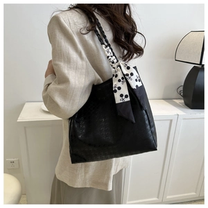 Detail of black tote bag with houndstooth embossing and elegant printed silk scarf