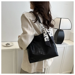 Detail of black houndstooth tote bag with silk scarf and woven handle on a model