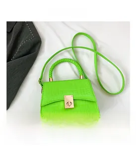 Detail of neon green crocodile texture handbag with woven handle and gold twist lock