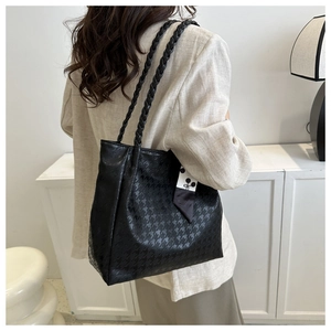 Detail of black houndstooth embossed tote bag with braided straps and decorative scarf
