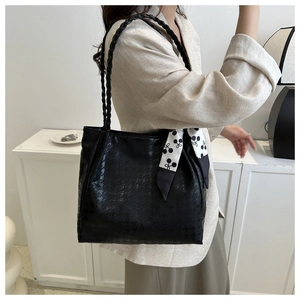 Close-up of black tote bag with houndstooth texture, braided strap and silk scarf