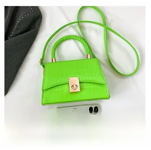 Detail view of fluorescent green crocodile pattern handbag with gold clasp and woven handle