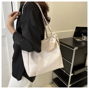 Detail of cream large tote bag with woven handles and silk scarf in a lifestyle setting