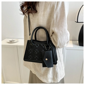 Detail van zwarte trapeziumtas met klaverreliëf en afneembare bijpassende mini-pochette