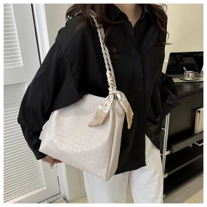Detail of cream tote bag with houndstooth texture, woven strap and silk scarf accessory