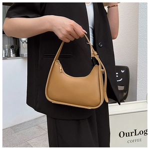 Chic camel-colored crescent underarm bag with adjustable strap shown in lifestyle setting