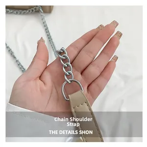 Detail of silver chain strap and beige PU leather stitching on shoulder bag