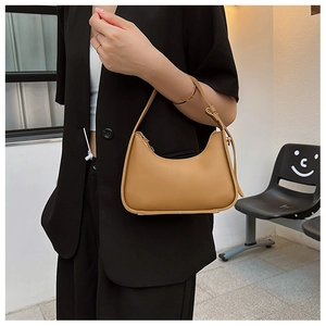 Detail of khaki crescent underarm bag with adjustable strap on a black blazer model