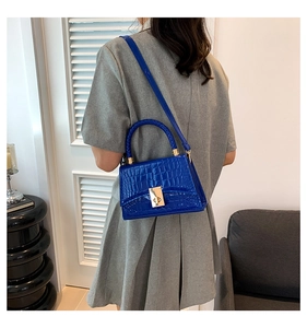 Detail of Klein blue crocodile texture handbag with gold metal clasp on model