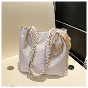 Detail of off-white tote bag featuring houndstooth texture and woven shoulder strap