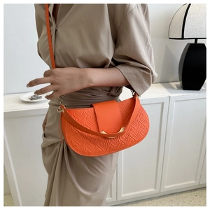 Detail van de oranje zadeltas met hartjesreliëf en goudkleurige metalen accenten