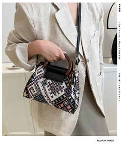 Detailed side view of vintage geometric woven bucket bag with wood handle on model
