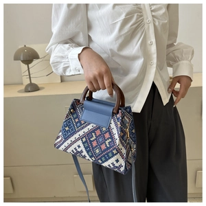 Close-up of ethnic woven pattern fabric with round wooden handles and blue leather flap