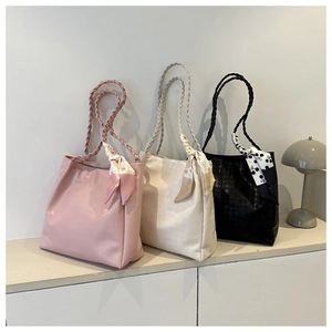 Close-up of three faux leather tote bags with woven handles and decorative silk scarves