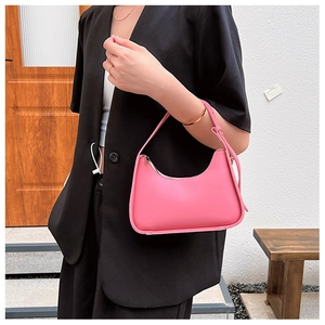 Detailed view of pink minimalist PU leather shoulder bag on model wearing black blazer