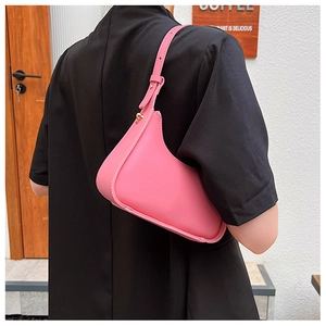 Side view of a pink minimalist underarm crescent bag with adjustable golden hardware