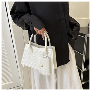 Detail van de witte handtas met klaverpatronen en bijpassende kaarthouder