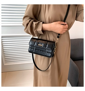 Detail van zwarte gewatteerde leren crossbodytas met gouden metalen gesp en ketting