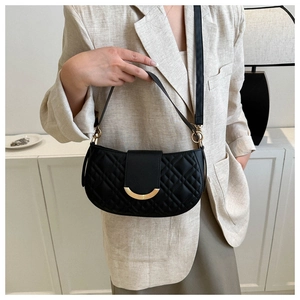 Detail van zwarte gewatteerde zadeltas met gouden sluiting op beige linnen blazer