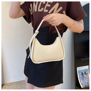 Detail of a beige half-moon hobo bag with adjustable strap held by a model