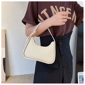 Detail of a cream crescent underarm bag with smooth leather and gold metal zipper