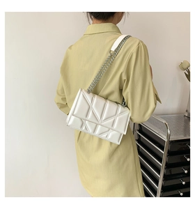 Close-up of white PU leather small square bag with geometric triangle quilting and chain