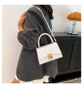 Close-up of a white faux crocodile skin handbag featuring a golden twist-lock closure
