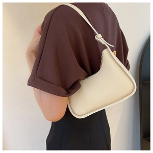 Détail d'un sac sous le bras blanc en forme de croissant avec fermeture éclair dorée
