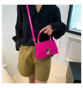 Detail of rose pink crocodile pattern patent leather handbag with gold metal clasp
