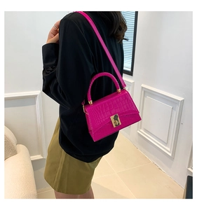 Detail of rose red handbag with crocodile pattern texture and golden square lock