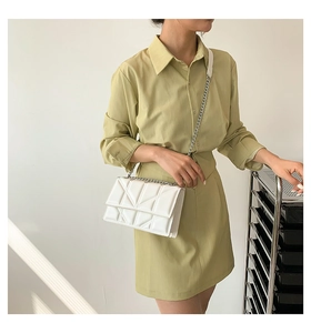 White geometric quilted leather chain bag carried by a model in a minimalist setting