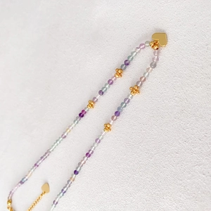 Collier de perles colorées avec pierres facettées et pendentif cœur sur fond gris