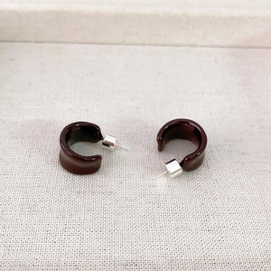 Minimalist deep burgundy resin C-shape hoop earrings with silver pins on beige linen texture