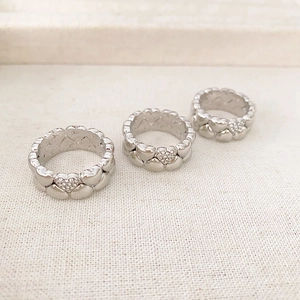 Three stacked silver-colored heart rings with sparkling crystals and polished finish