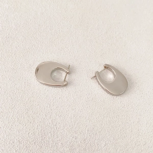 Minimalist shiny silver U-shaped hoop earrings with a sleek modern design on a textured base