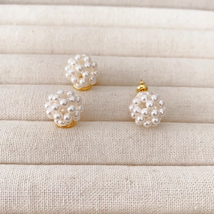 Handmade woven pearl cluster earrings with 925 silver needles on beige jewelry display