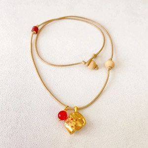 Handwoven necklace featuring a golden elephant pendant and a vibrant red bead accent