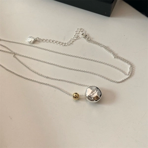 Detailed close-up of textured irregular silver disc necklace with gold bead and midnight engraving