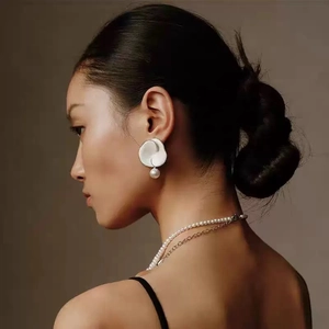 Boucles d'oreilles fleurs blanches avec perles sur mannequin sur fond chaleureux