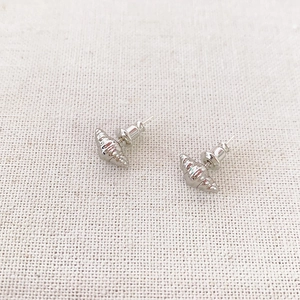 Minimalist silver croissant stud earrings with realistic spiral texture on linen fabric